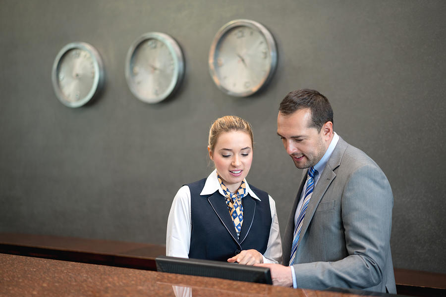 Hotel manager talking to woman at the front desk Photograph by Andresr