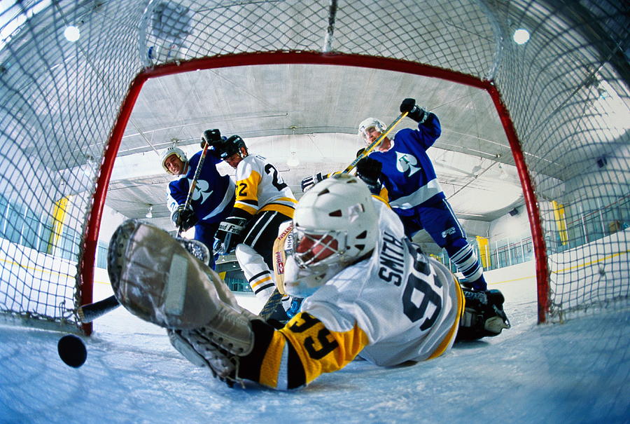 Ice hockey, goalie reaching for puck rolling into goal (wide angle) Photograph by David Madison