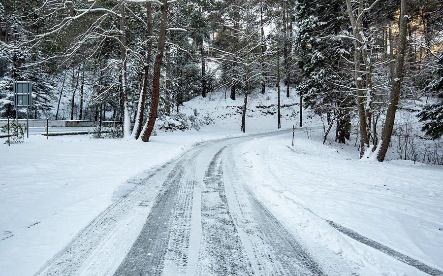 Icy slippery dangerous road in winter in the forest. Snowy mountains snowstorm. Photograph by Michalakis Ppalis
