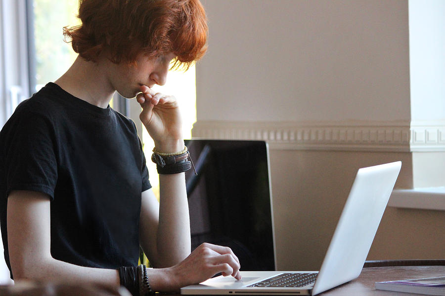 Image of teenage boy doing homework on laptop computer Photograph by Mtreasure
