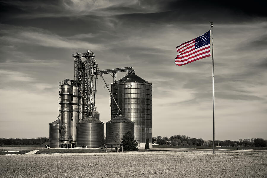 Black And White Photograph - Big Ag, Big Flag  - Klondike farms grain handling site with huge flag  by Peter Herman