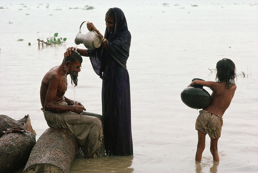 India, Bangladesh, woman standing in river washing mans hair... Photograph by Christopher Pillitz