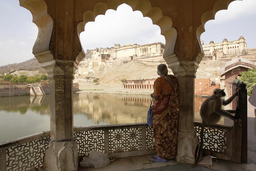 India, Rajasthan, woman standing on veranda, Amber Fort in distance Photograph by Thomas Brown