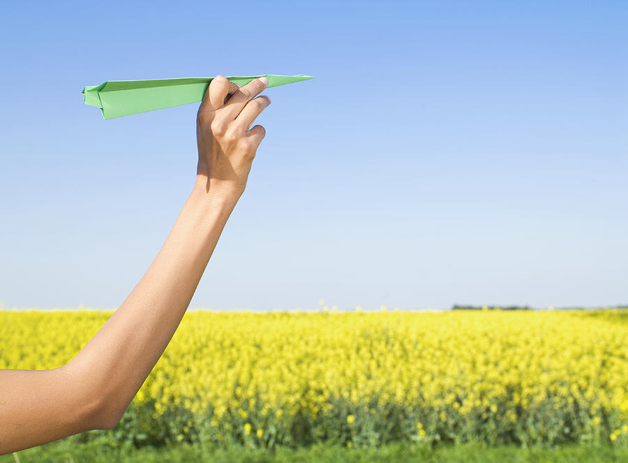 Indian woman holding green paper airplane in field of flowers Photograph by Jacobs Stock Photography Ltd