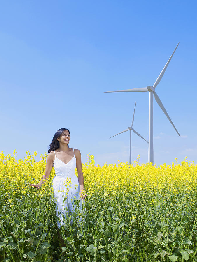 Indian woman standing in field near wind turbines Photograph by Jacobs Stock Photography Ltd