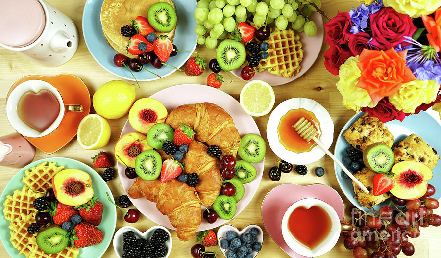 Indulgent breakfast flat lay with croissants, pancakes, waffles, and fruit. Photograph by Milleflore Images