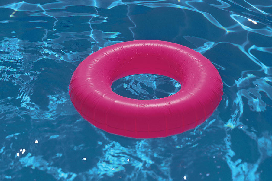 Inner tube floating in swimming pool Photograph by Comstock