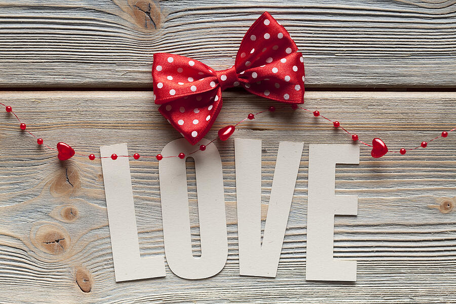 Inscription love and a red bow on wooden background Photograph by Tedestudio