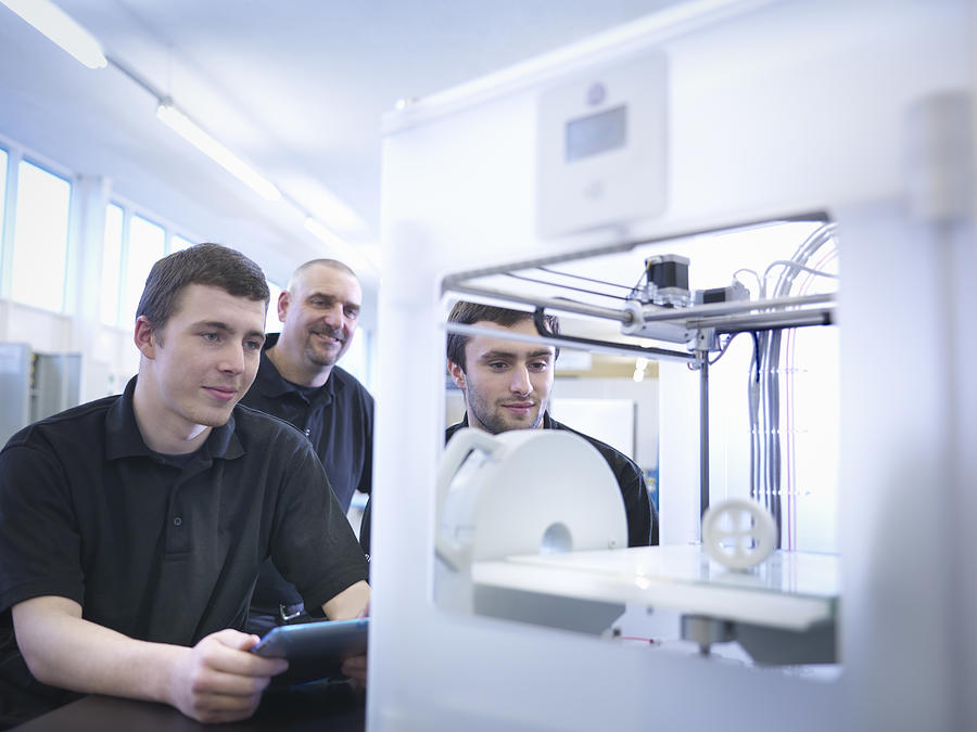 Instructor with apprentices and 3D printing machine Photograph by Monty Rakusen