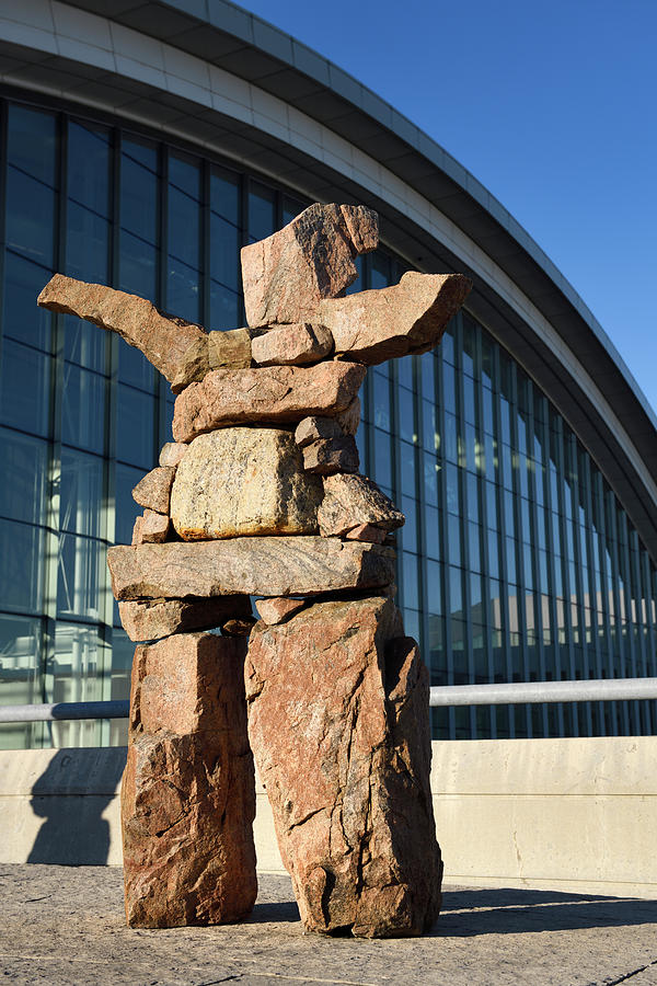 Inukshuk red stone statue with outstretched welcoming arms at Pe ...