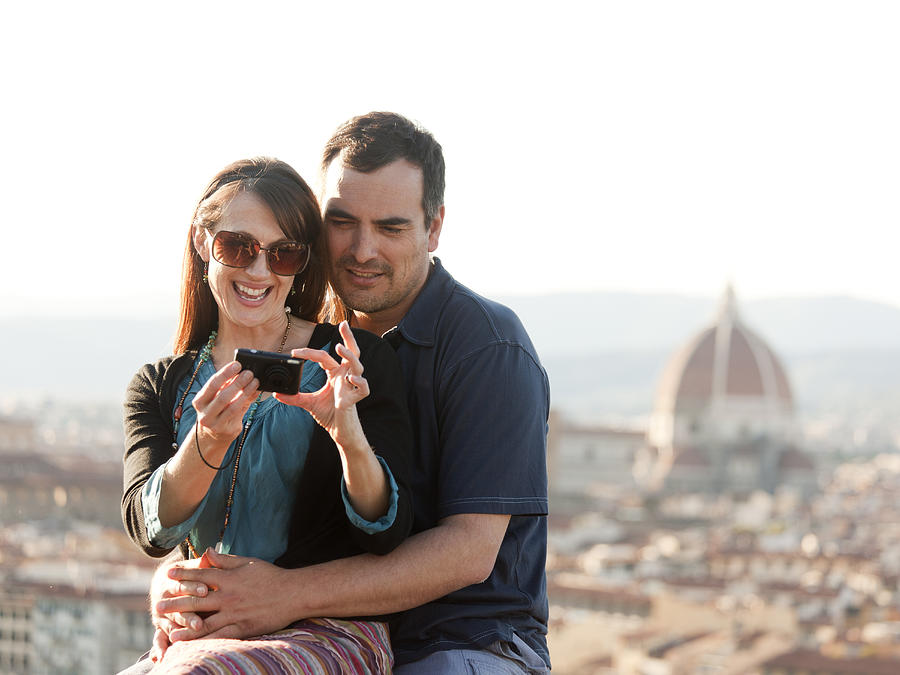 Italy, Florence, Couple viewing camera at lookout over old town Photograph by Rubberball/Alan Bailey