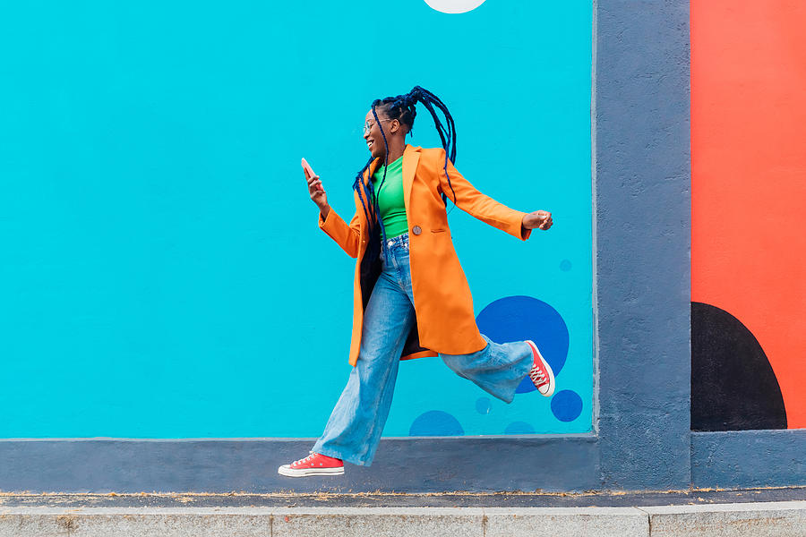 Italy, Milan, Woman with braids jumping against blue wall Photograph by Eugenio Marongiu