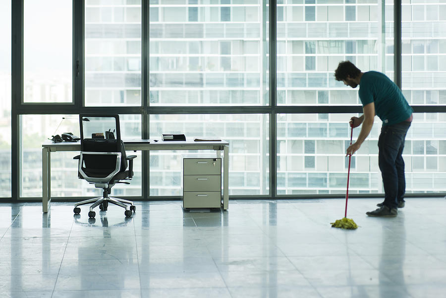 Janitor mopping empty office Photograph by Frederic Cirou/PhotoAlto