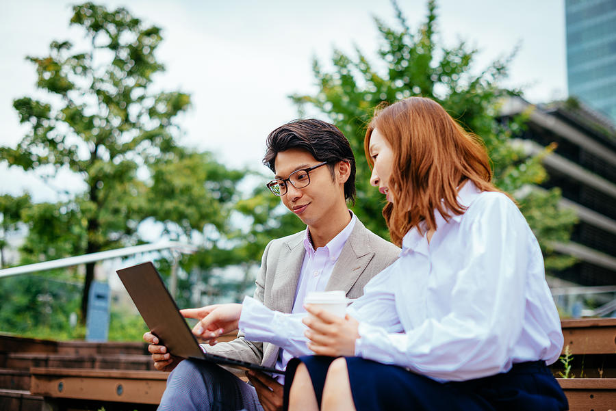 Japanese business people using laptop on coffee break Photograph by Drazen_