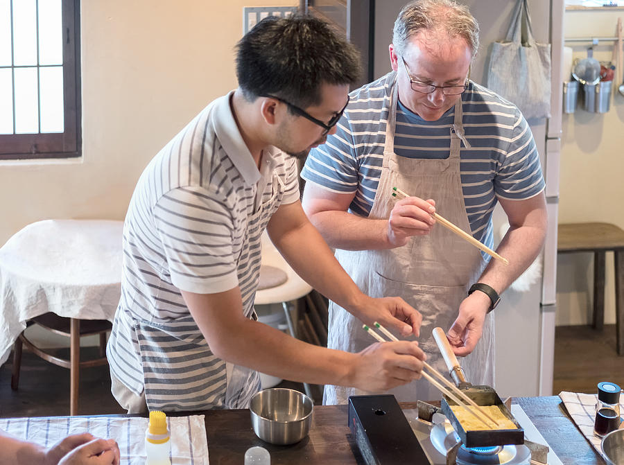 Japanese Man Teaching Caucasian Man How to Cook Tamagoyaki Omelette Photograph by PamelaJoeMcFarlane