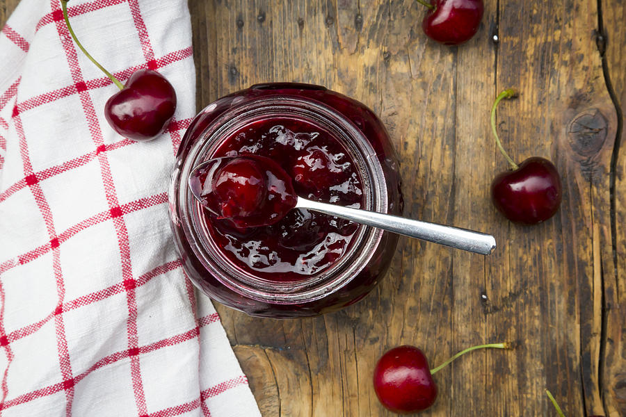 Jar of homemade cherry jam and cherries on wood Photograph by Larissa Veronesi