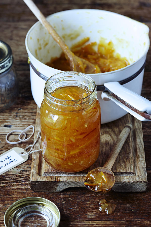 Jar of marmalade on table with pan Photograph by Martin Poole