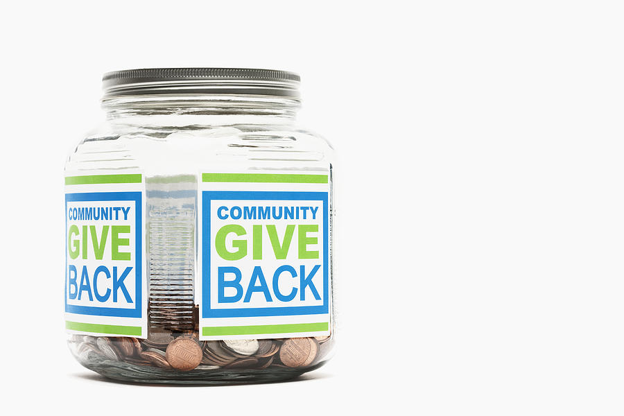 Jar of pennies with community give back sticker Photograph by Fuse