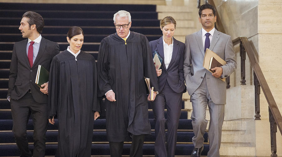 Judges and lawyers walking through courthouse together Photograph by Caia Image