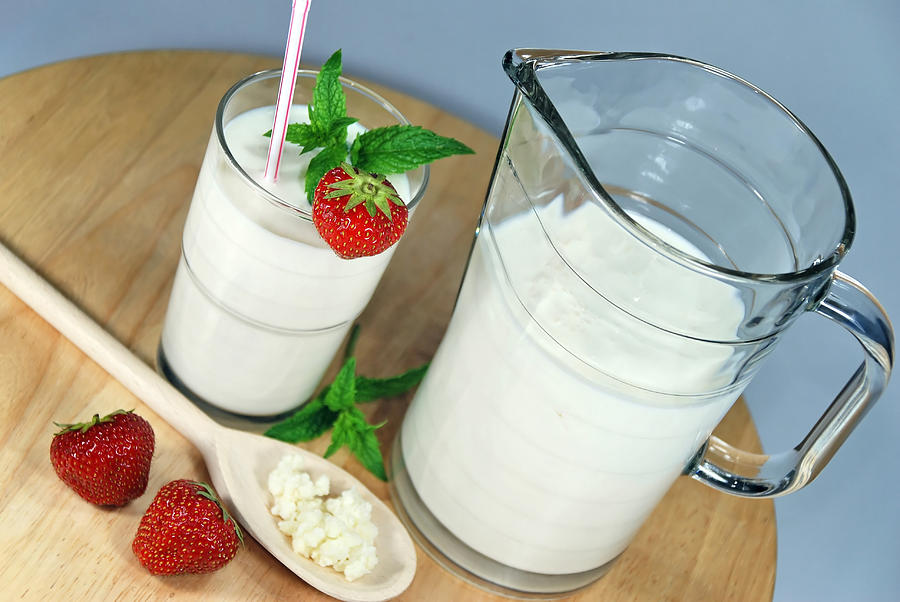 Jug and glass of kefir, decorated with fresh strawberries Photograph by Esemelwe