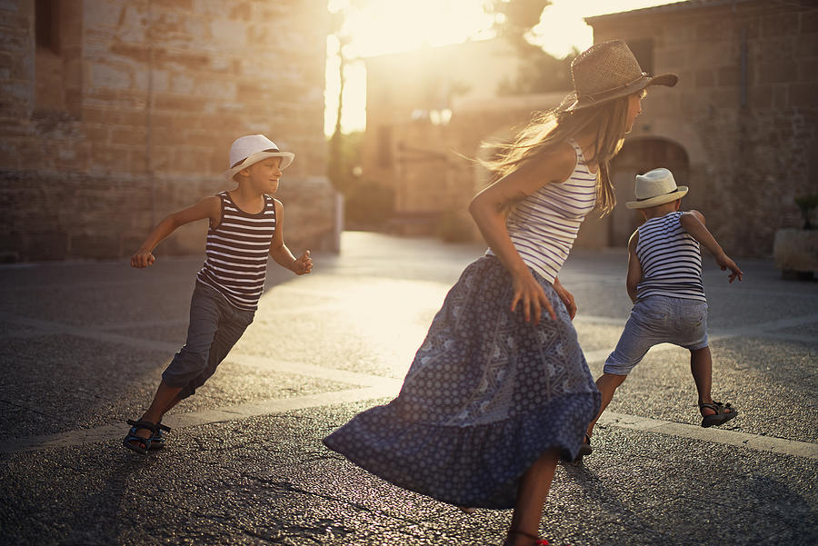 Kids tourists playing tag in mediterranean street. Photograph by Imgorthand