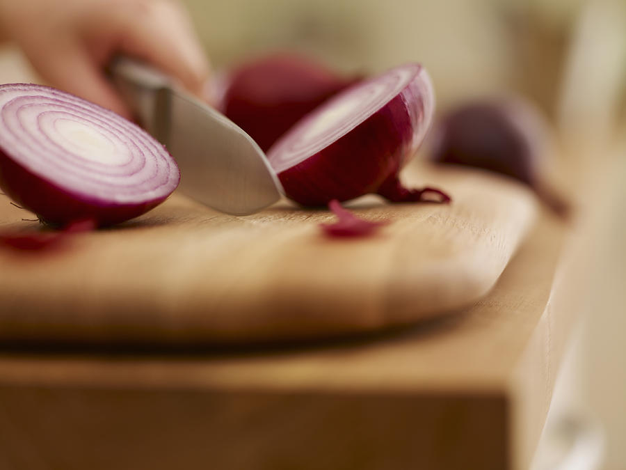 Knife chopping red onion on cutting board Photograph by Adam Gault