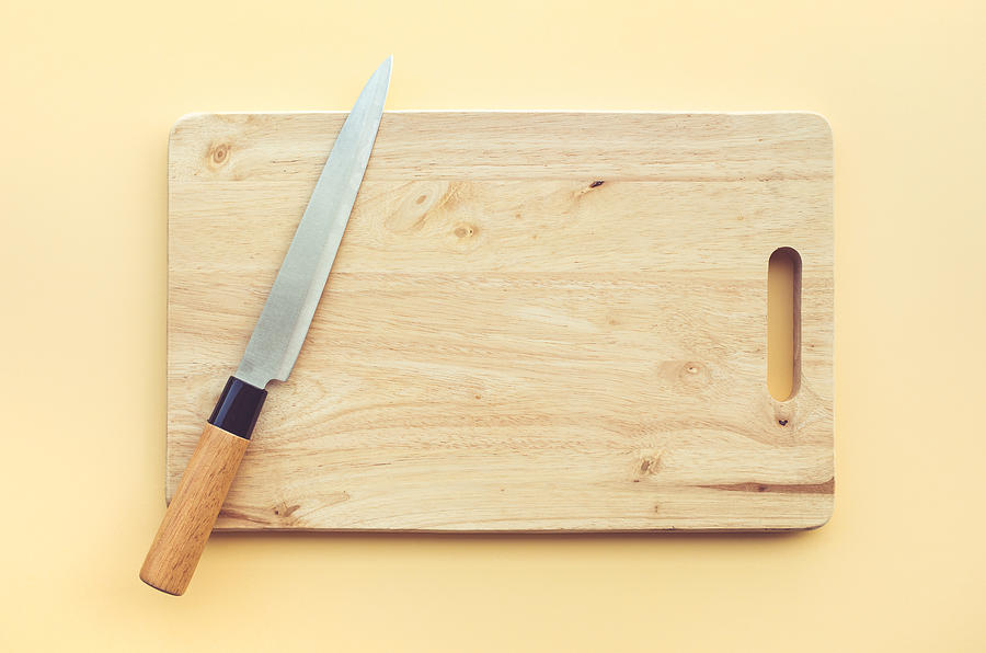 Knife on wooden chopping board on pastel color Photograph by Hakinmhan