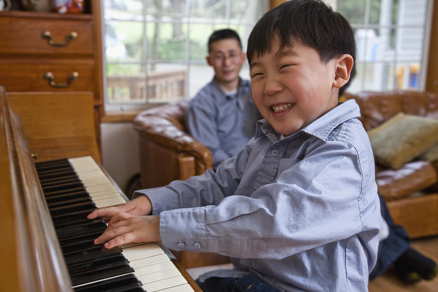Korean boy playing piano Photograph by Blend Images