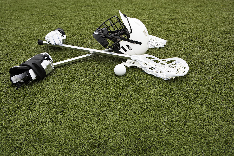 Lacrosse sticks, gloves, balls and sports helmet on artificial turf Photograph by Thomas Northcut