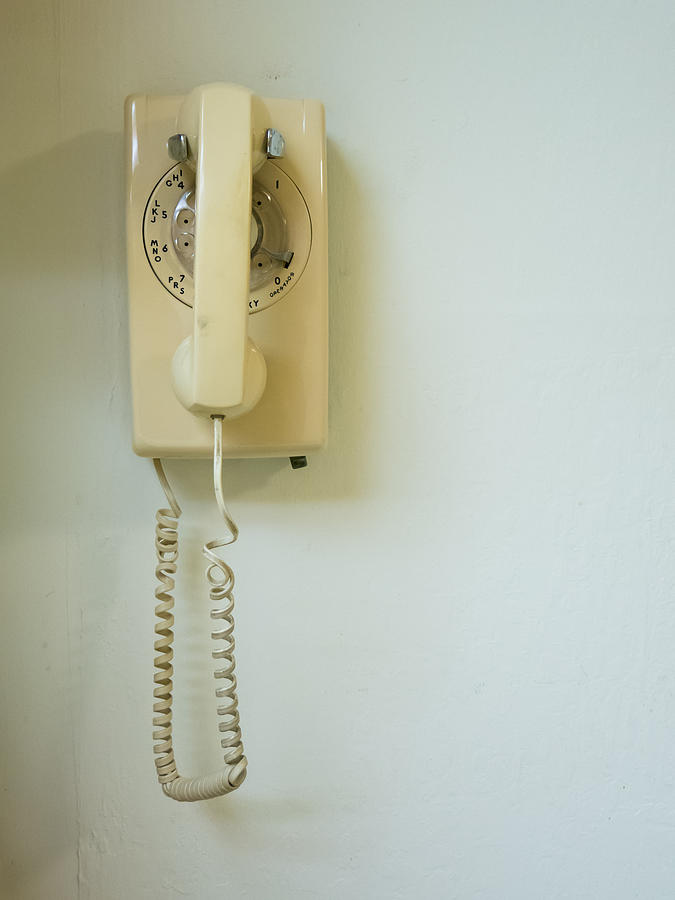 Landline home telephone hanging on wall Photograph by Jason Todd