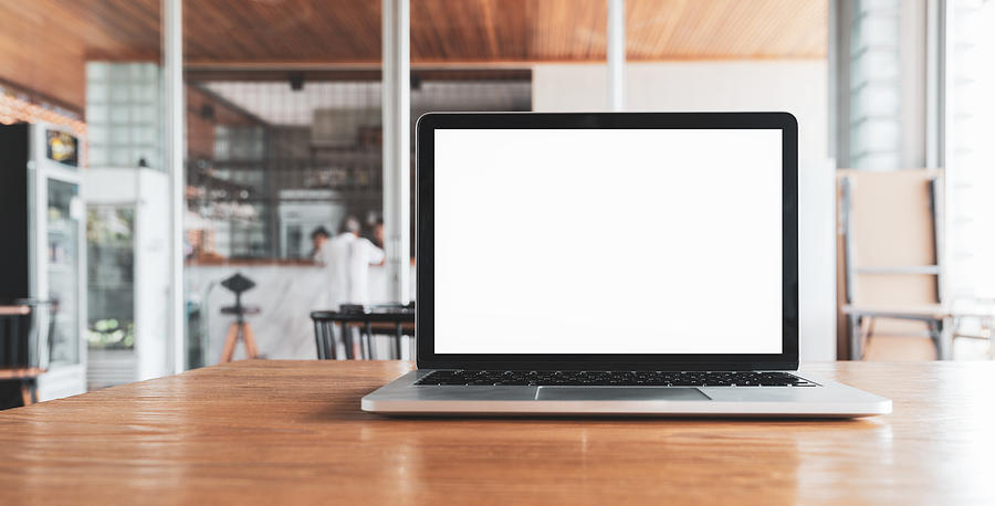 Laptop computer blank white screen on table in cafe background. Laptop with blank screen on table of coffee shop blur background. Photograph by TravelCouples
