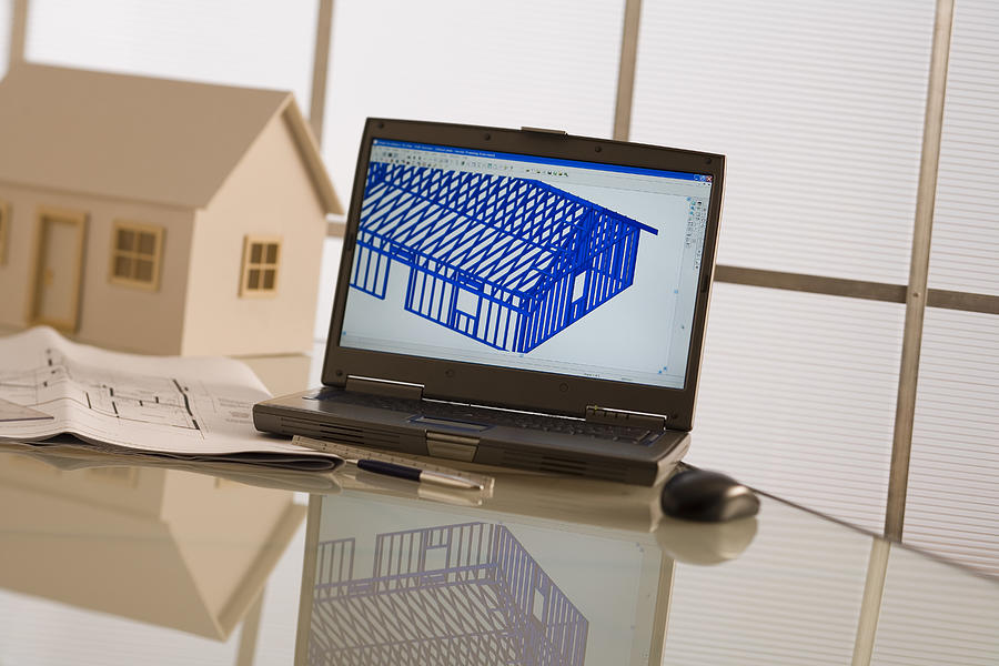 Laptop, model house, and blueprints Photograph by Comstock Images