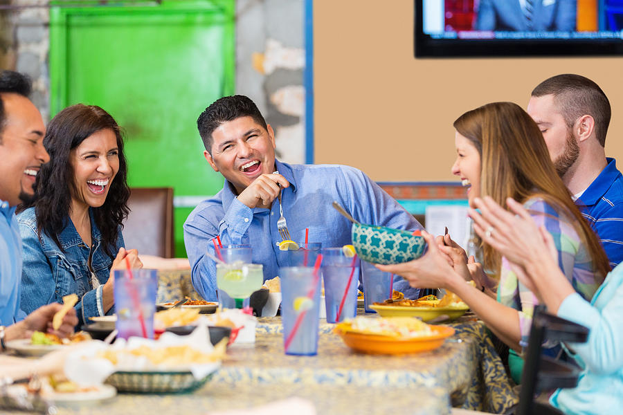Large group of friends laughing during dinner in Tex-Mex restaurant Photograph by SDI Productions