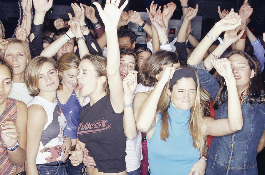 Large group of teenagers dancing at club, front view Photograph by David De Lossy