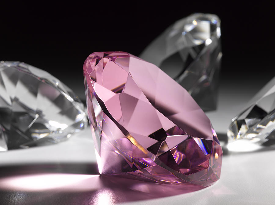 Large pink diamond surrounded by clear diamonds, close-up (still life) Photograph by Jeffrey Hamilton