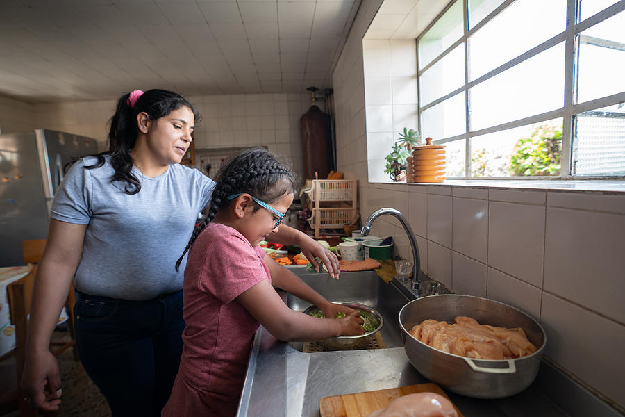 Latin American mother teaching her daughter to cook Photograph by Andresr Latin American mother teaching her daughter to cook Photograph by Andresr