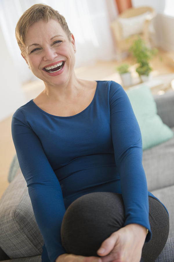Laughing Caucasian woman sitting on sofa Photograph by JGI/Jamie Grill
