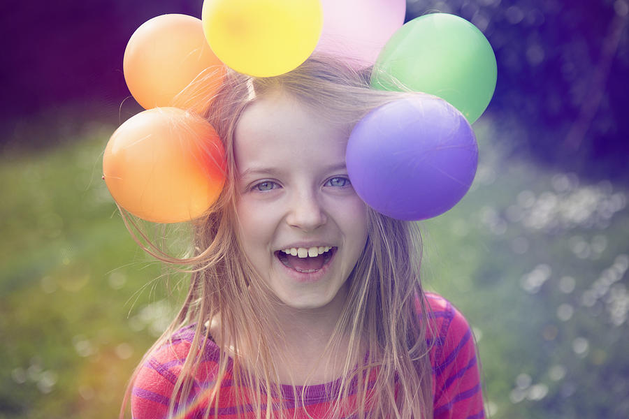 Laughing child with balloons stuck on her head Photograph by Elva Etienne