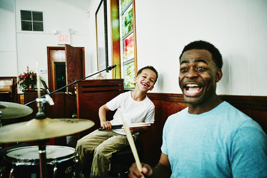 Laughing father and son playing on drum set Photograph by Thomas Barwick