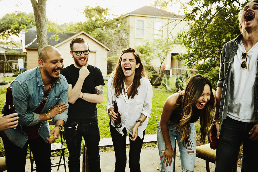 Laughing  friends in backyard on summer evening Photograph by Thomas Barwick
