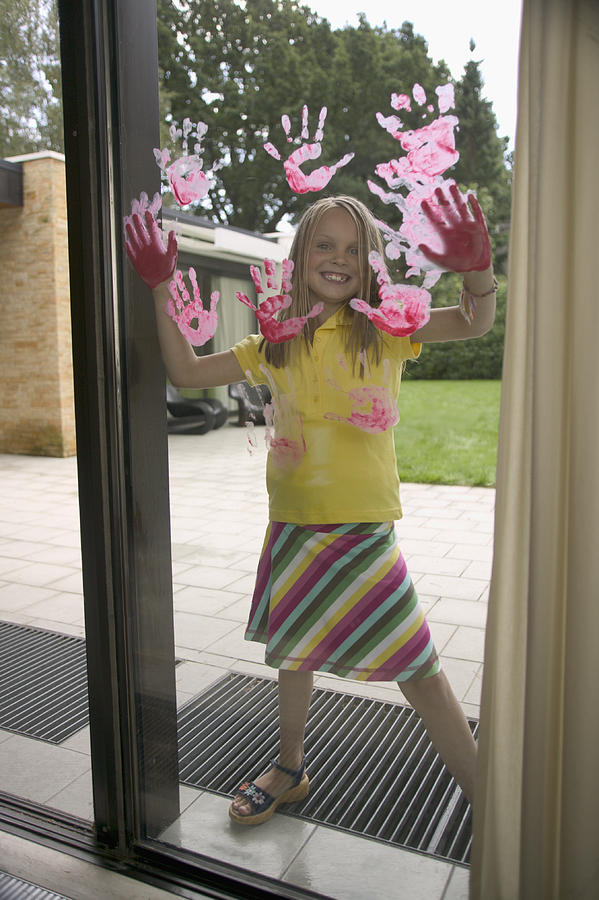 Laughing girl hand painting window pane Photograph by Fuse