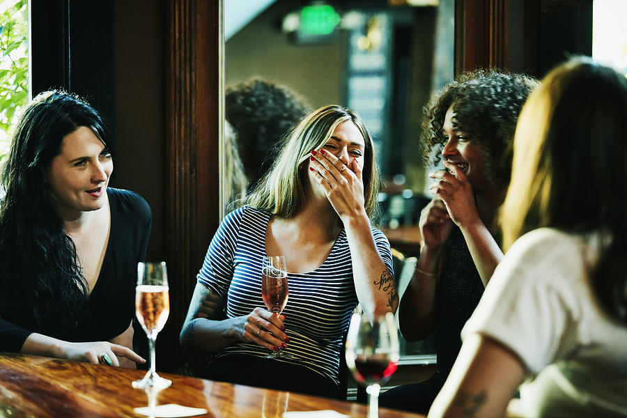 Laughing group of women enjoying drinks in bar Photograph by Thomas Barwick