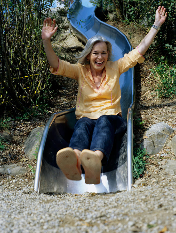 Laughing woman on slide. Photograph by Image Source