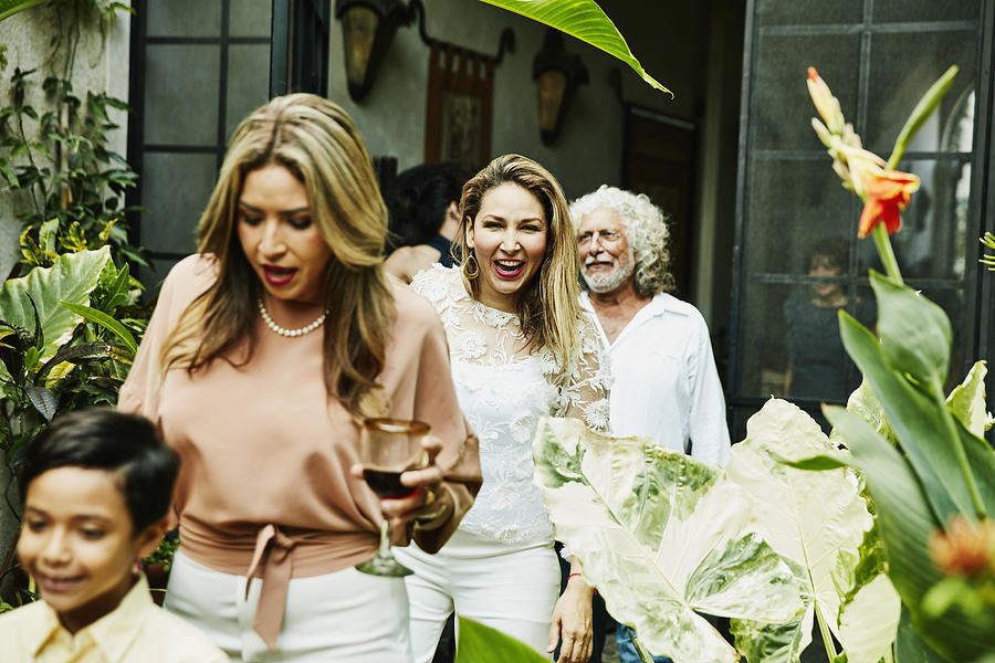 Laughing woman walking into backyard with family during dinner party Photograph by Thomas Barwick