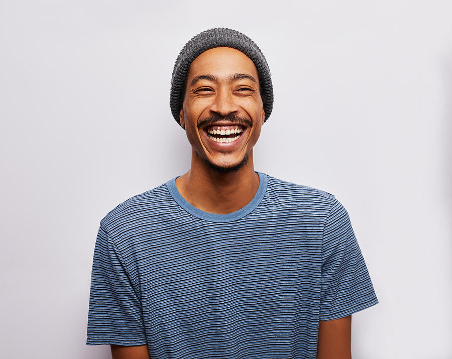 Laughing young man standing against a gray background Photograph by Goodboy Picture Company