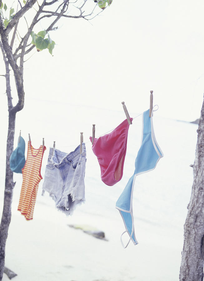 Laundry hanging on clothes line between trees at ocean Photograph by Steve Mason