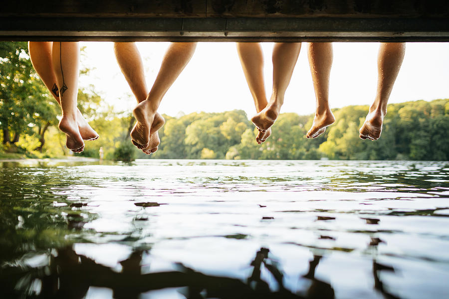 Legs Dangling Over Water At Lake Photograph by TommL