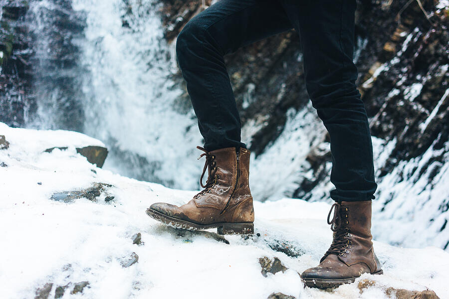 Legs in boots on the background of waterfall in winter Photograph by High Fidelity Studio