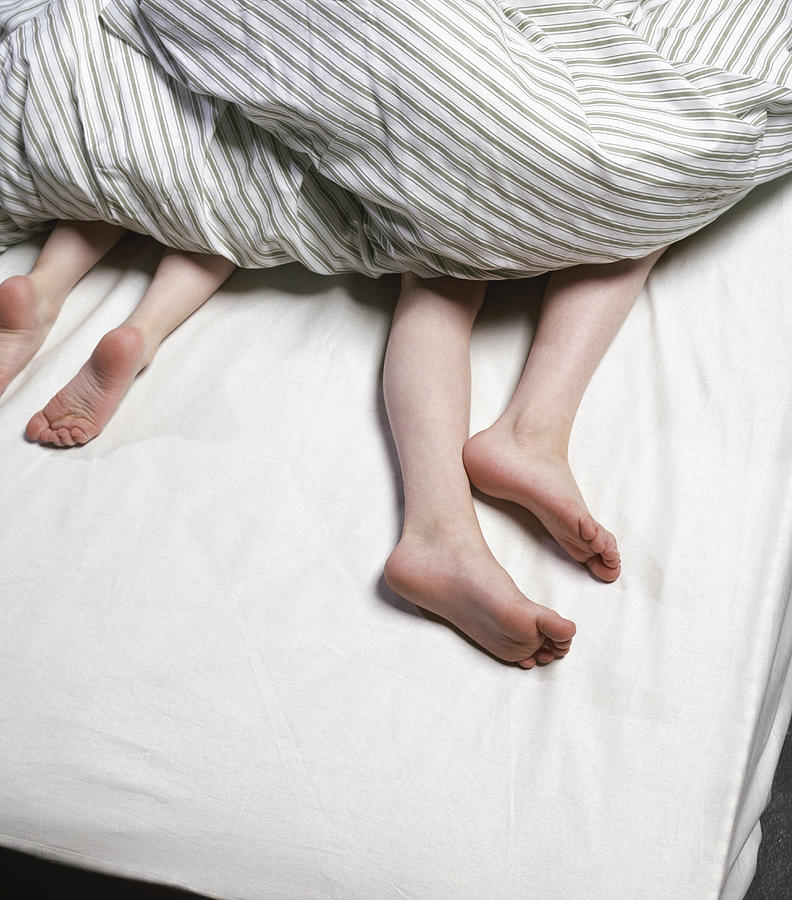 Legs of boys under duvet Photograph by Atli Mar Hafsteinsson