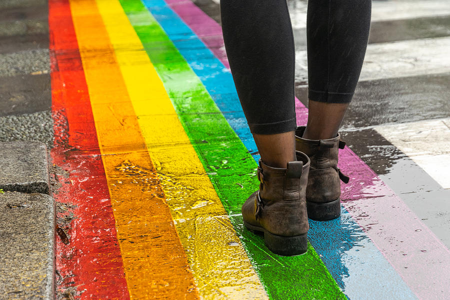 Legs walking on Gay rainbow crosswalk. Photograph by Beli_photos